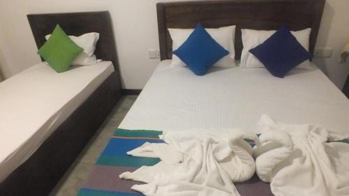 a bedroom with two beds with white sheets and blue pillows at Buddika Safari & Resort in Udawalawe