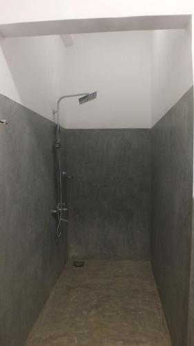 a shower in a bathroom with a gray wall at Buddika Safari & Resort in Udawalawe
