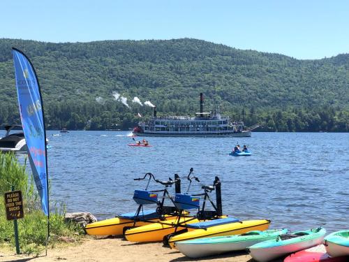 a large boat on a lake with people in kayaks at Scotty's Lakeside Resort in Lake George