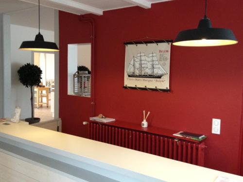 a red wall with a picture of a ship on it at Hôtel Le Vert Bois in Dolus d'Oléron