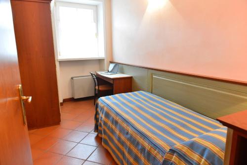 a bedroom with a bed and a desk and a window at Residence Del Messaggero in Rovereto