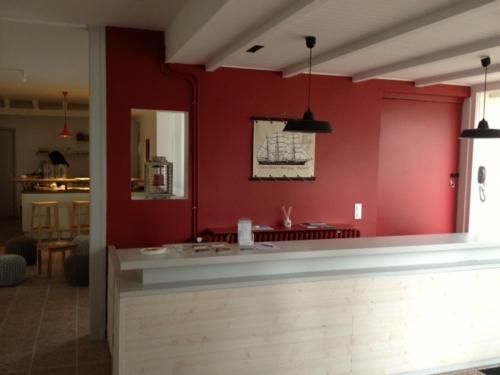 a room with a red wall with a counter in it at Hôtel Le Vert Bois in Dolus d'Oléron