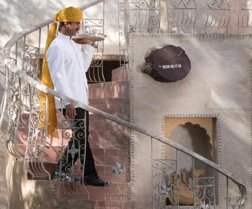 a man standing on a staircase holding a plate at Ajit Bhawan - A Palace Resort in Jodhpur