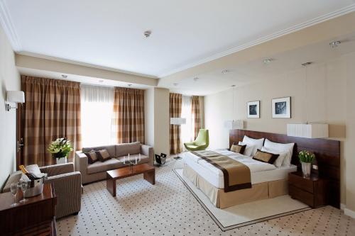 a hotel room with a large bed and a couch at Capital Plaza Hotel in Bucharest