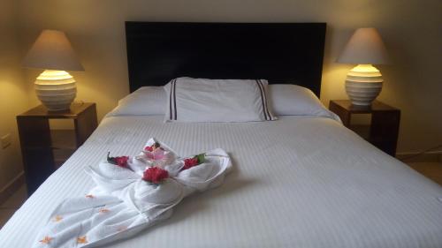 a white bed with flowers on it with two lamps at Villa Creole in Jacó