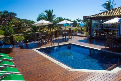 a pool with tables and chairs on a wooden deck at Coronado Inn Hotel in Búzios