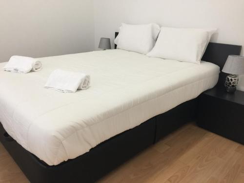 a large bed with white sheets and pillows on it at Invicta House Maia in Maia