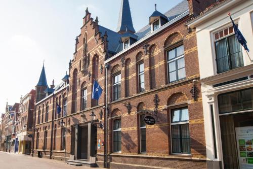 a large brick building with flags on a street at Fletcher Hotel Gilde in Deventer