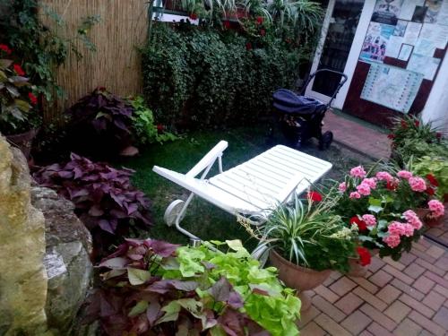 a white bench sitting in a garden with flowers at Unicum Vendégház in Abádszalók