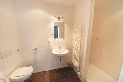a white bathroom with a toilet and a sink at Fletcher Hotel Gilde in Deventer