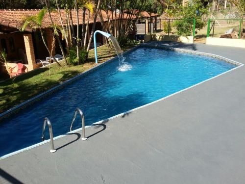 a swimming pool with a water fountain in it at Aconchego Caminho das Cachoeiras in Rio Acima