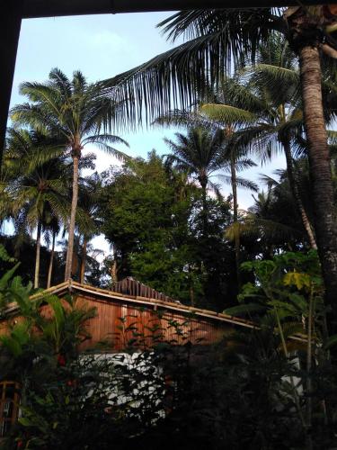 a wooden fence with palm trees in the background at Pousada Pérola do Atlântico in Ilha de Boipeba