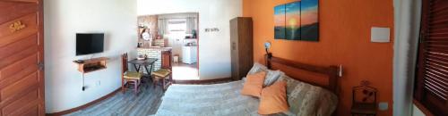 a living room with a bed and a television at Estúdio Recanto Dos Anjos in Arraial do Cabo