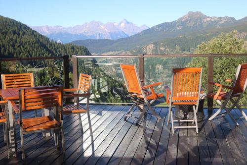 four chairs and a table on a deck with mountains at Maison Cly in Chamois