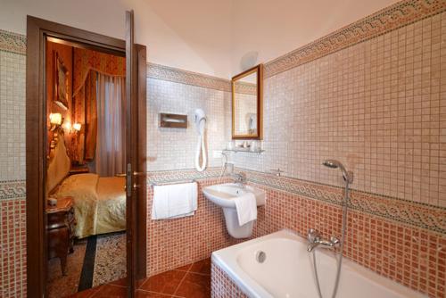 a bathroom with a tub and a sink and a bed at Residenza Hotel San Maurizio in Venice