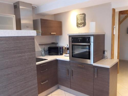 - une cuisine avec des placards en bois et un four micro-ondes dans l'établissement La Coulée Douce - Chez Antoine, à Castelnaudary