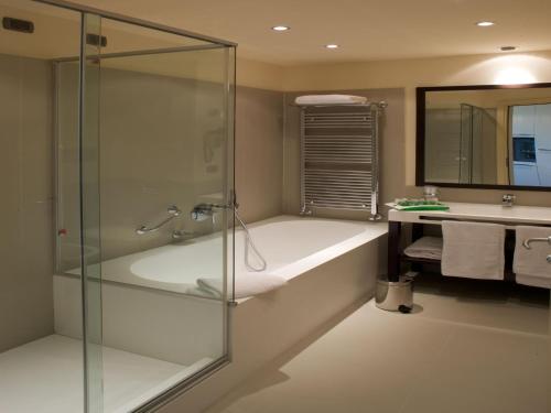 a bathroom with a tub and a glass shower at Grand Hotel Mattei in Ravenna