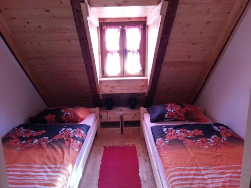 2 Betten in einem Dachzimmer mit Fenster in der Unterkunft Snašini kućari in Gradište
