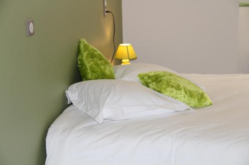 a bed with white sheets and green pillows at Les Chambres d'Eugénie in Poyanne