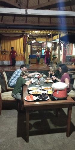 a group of people sitting around a table with food at Mandhasativa Homestay in Singaraja