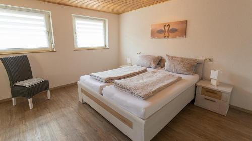 biała sypialnia z łóżkiem i krzesłem w obiekcie Ferienwohnung Dürr w mieście Dorfprozelten