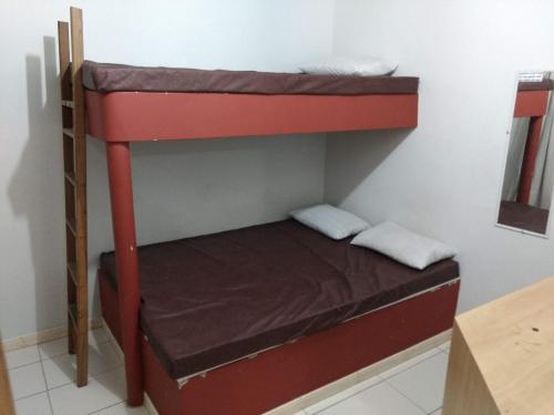 a bunk bed in a small room with a bed on top at Edificio Netuno in Cabo Frio
