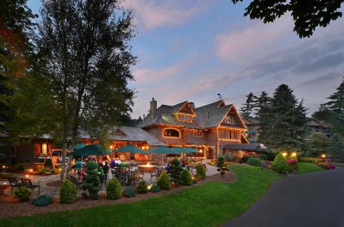 ein großes Haus mit einer Terrasse mit Tischen und Sonnenschirmen in der Unterkunft Chetola Resort at Blowing Rock (Lodge) in Blowing Rock