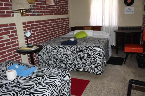 a room with two beds and a brick wall at Hotel Casa Del Viajero in Quetzaltenango
