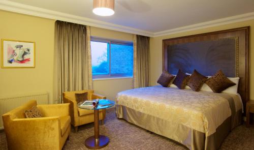 a hotel room with a bed and a chair at Aubrey Park Hotel in Hemel Hempstead