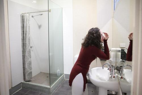 Una mujer parada en un baño junto a un lavabo en Barkly Backpackers, en Melbourne