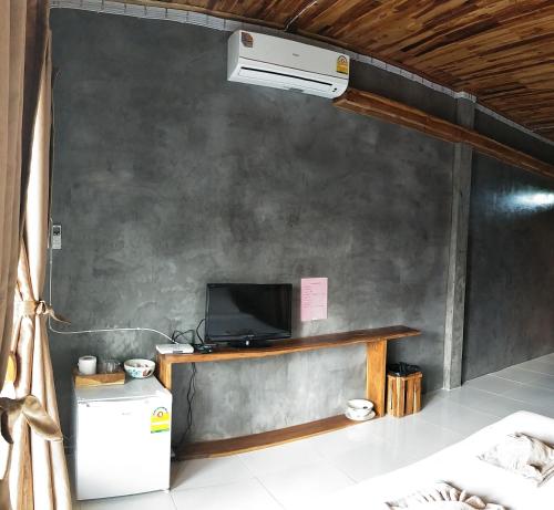a living room with a tv and a refrigerator at Teak villa in Thoeng