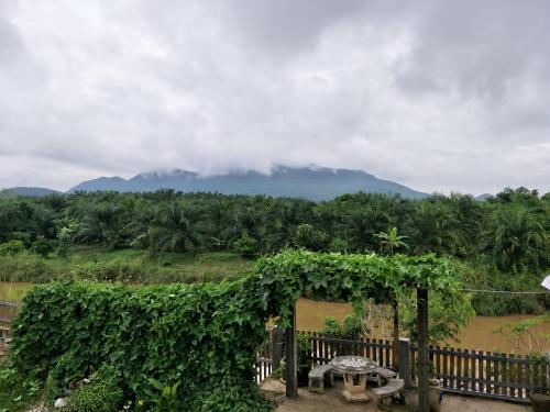 a garden with a table and a fence with mountains in the background at Teak villa in Thoeng