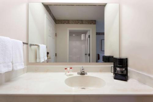 a bathroom with a sink and a large mirror at Ramada by Wyndham SeaTac Airport North in Tukwila