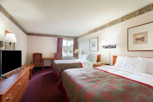 a hotel room with two beds and a flat screen tv at Ramada by Wyndham SeaTac Airport North in Tukwila