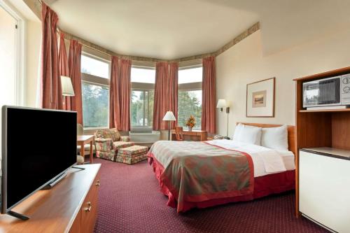a hotel room with a bed and a flat screen tv at Ramada by Wyndham SeaTac Airport North in Tukwila