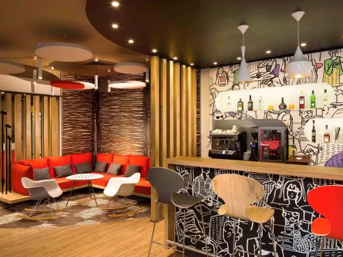 a restaurant with a bar with red chairs and a counter at Ibis Budapest Heroes Square in Budapest