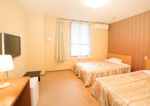 a hotel room with two beds and a television at Itoen Hotel Shiobara in Nasushiobara
