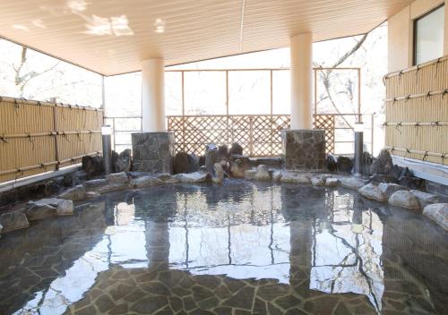 a pool of water in a large room with rocks at Itoen Hotel Shiobara in Nasushiobara