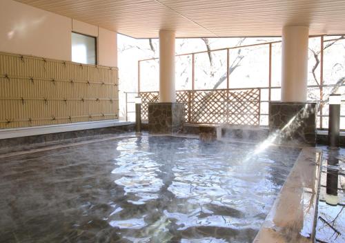 a pool of water in a room with a fountain at Itoen Hotel Shiobara in Nasushiobara