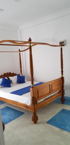 a wooden bed in a room with blue pillows at Fairview Residence in Kandy