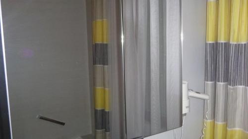 a bathroom with a shower with a yellow and white curtain at Pension Wildental in Sankt Martin bei Lofer