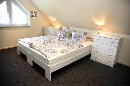 ein Schlafzimmer mit einem weißen Bett, einer Kommode und einem Fenster in der Unterkunft Ferienwohnung „Kranich“ in Mirow