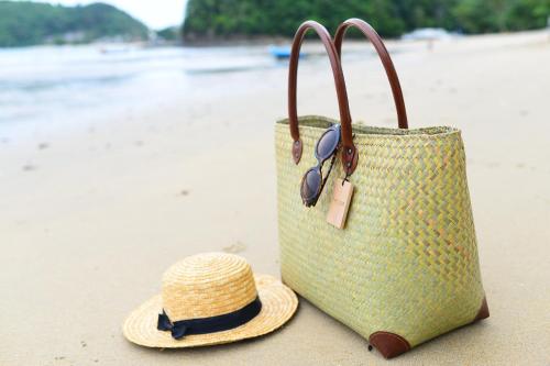 a straw purse and a straw hat on the beach at The Cove in Panwa Beach
