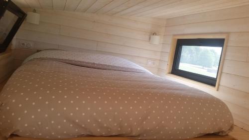 uma cama num pequeno quarto com uma janela em La Tiny du Parc : Saint Symphorien des Monts em Saint-Symphorien-des-Monts