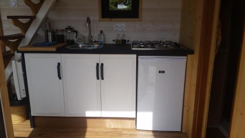 a kitchen with white cabinets and a sink at La Tiny du Parc : Saint Symphorien des Monts in Saint-Symphorien-des-Monts