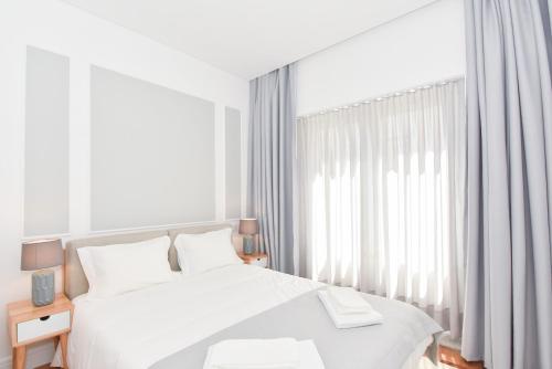 a white bedroom with a bed and a window at Oporto Lovely House in Porto
