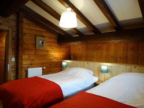 two beds in a room with wooden walls at Chalet Des Sangliers in Séez