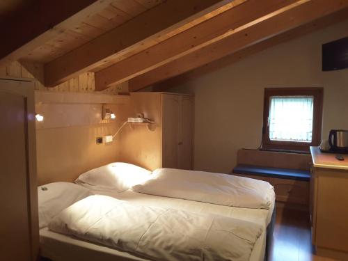 a bedroom with a bed with white sheets and a window at B&B Chalet Brigitte Hike & Bike in Arabba