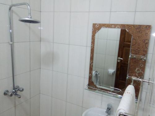 ein Bad mit einer Dusche, einem Spiegel und einem Waschbecken in der Unterkunft Cashewnut Hotel in Mtwara