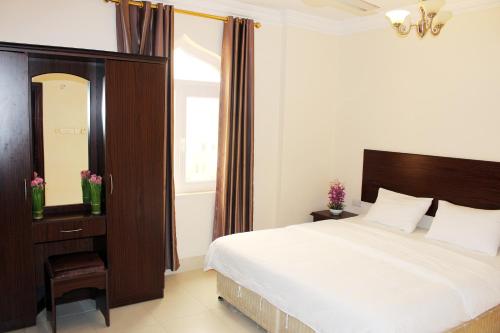 a bedroom with a large bed and a mirror at Al Noor Furnished Flats in Salalah